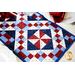 A close up of the beautiful red, white, and blue geometric blocks in the 4-Patch Pinwheel Table Runner