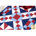 A close up of the beautiful red, white, and blue geometric blocks in the 4-Patch Pinwheel Table Runner