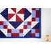 A close up of the beautiful red, white, and blue geometric blocks in the 4-Patch Pinwheel Table Runner