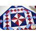 A close up of the beautiful red, white, and blue geometric blocks in the 4-Patch Pinwheel Table Runner
