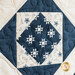 Quilt with geometric designs of squares and diamonds in blue and cream fabrics.