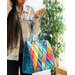 woman with brown hair holding a handmade bag with a diamond pattern in rainbow colors