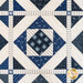 A patchwork quilt featuring blue and white geometric patterns with star motifs and intricate stitching.