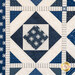 Close-up of a quilt featuring blue patterns and star motifs with a geometric design.