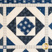 Close-up of a blue and white quilt featuring star patterns and diamond shapes.