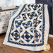 A blue and white quilt with geometric patterns draped over a wooden chair in a cozy room.