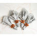 A set of 4 light colored cloth napkins with fringed edges wrapped in faux leather napkin rings