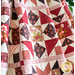Quilt with geometric piecing made of red, pink, and cream floral fabrics.