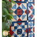 Stars and stripes quilt made of geometric blocks featuring red, blue, and cream, patriotic fabric prints.