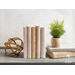 A collection of books with fabric book covers standing on a shelf next to a small plant and home decor