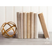 A collection of books with fabric book covers standing on a shelf next to a modern decor piece