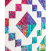 A colorful purple, pink, and teal batik block on a white quilt background