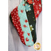 Christmas stocking made of various holiday themed fabrics hanging on a white wall.