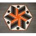 Halloween themed table topper with diamonds made of strips of black and orange fabric on a white background with black cat face appliqué.