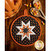 Round hot pad made of black fabric with candy corn print along with orange and white accent fabrics.
