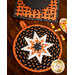 Round hot pad made of black fabric with candy corn print along with orange and white accent fabrics.