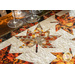 Table runner with two rows of maple leaves made of autumn themed prints on cream background.