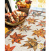 Table runner with two rows of maple leaves made of autumn themed prints on cream background.