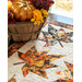 Table runner with two rows of maple leaves made of autumn themed prints on cream background.