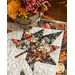 Close up of a table runner with a autumn themed maple leaf in the corner.