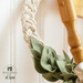 Beige wreath made with a braided design and green leaves made of fabric accented with a beige ribbon, close up on the braided wreath.
