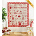 Cream, pink, and red quilt featuring flowers and animals, hanging on white wood panel wall.