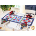 A red, white, and blue table runner made with floral fabrics laid flat on a white table next to cloth napkins