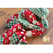angled view of four red and green Christmas themed napkins in rings, fanned together atop a brown wooden table