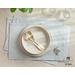 Light blue placemats with floral embroidery in the lower right corner set with dinnerware.