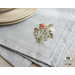 Light blue placemats with floral embroidery in the lower right corner set with dinnerware.