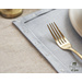 Light blue placemats with floral embroidery in the lower right corner set with dinnerware.
