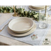 Light blue placemats with floral embroidery in the lower right corner set with dinnerware.