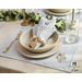 Light blue placemats with floral embroidery in the lower right corner set with dinnerware.