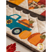 Table runner with square and triangle design with autumn themed fabrics and a truck with pumpkins appliqué on the ends.