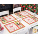 Placemats featuring a Christmas themed cross stitch sample panel print set on a table with silverware.
