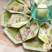 10 sided folded wreath being used as table topper with candle in the middle made of green and purple floral fabrics.