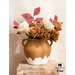 Gold and white paper flowers and red paper leaves with stems in a clay vase.