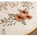 Embroidery hoop with hand embroidery featuring florals and the word home.