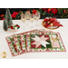 set of 4 placemats arranged in a fan on a white table with wine glasses, napkins on a plate, and trees with a bowl of ornaments and Christmas garland in the background