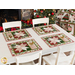4 placemats with silverware set in front of chairs at a white table with a fireplace and Christmas decorations in the background