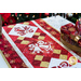 Christmas themed table runner featuring bell designs made of red and cream snowflake fabrics.