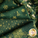 Photo of green fabric with metallic gold accents in snowflake, tree, bauble and star motifs.