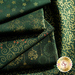 Photo of green fabric with metallic gold accents in snowflake, tree, bauble and star motifs.