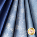 Close up of light blue fabric with metallic silver winter motifs layered atop one another