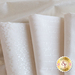 Array of folded white fabrics with pearlescent white swirls and script patterns