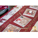 A festive table runner featuring holiday-themed illustrations, including Santa and a gingerbread man.