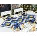 white table and chairs with christmas trees and a fireplace in the background, featuring a blue and gold table runner with gold place settings and matching napkins.