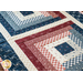 Table runner with four blocks of rectangular strips of fabric, featuring cream, read, and blue patriotic fabrics.