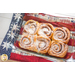 An close-up image of an Americana Casserole Hot Pad with a casserole dish of cinnamon rolls on a white table..