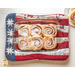 An image of an Americana Casserole Hot Pad with a casserole dish of cinnamon rolls on a white table.
